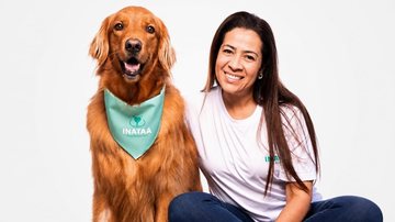 Foto de Gabriella, uma mulher branca de cabelos castanhos e longos com camiseta e jeans, e Zoff, um golden retriever usando uma bandana verde