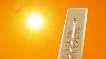 Termômetro marcando temperatura alta com sol brilhando ao fundo