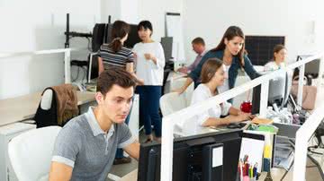 Jovens trabalham em frente a computadores