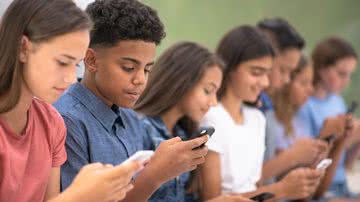 7 meninos e meninas adolescentes usando seus celulares lado a lado