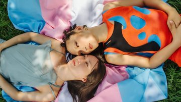 Duas pessoas trans deitadas em um gramado