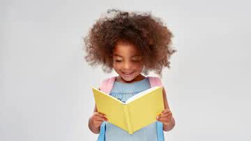Menina lê um livro e sorri.