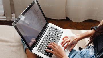 Pessoa digita em computador portátil