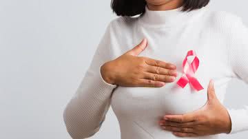 Mulher de blusa branca com fita rosa do Outubro Bosa no peito