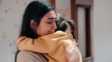 Mãe abraça filha criança