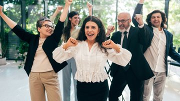 Homens e mulheres adultos em roupas de trabalho e ambiente corporativo comemoram juntos