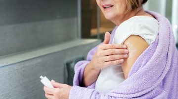 Mulher aplica creme no braço