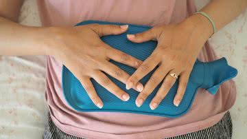 Mulher com bolsa de compressa na barriga