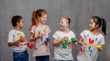 Quatro crianças, uma delas portadora de síndrome de Down, brincam com tintas juntas