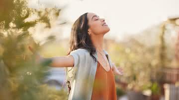 Mulher com braços abertos e sorrindo