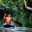 Homem indígena navega no rio em pequena canoa