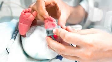 Adulto coloca medidor em pé de bebê prematuro