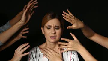 Mulher ansiosa com várias mãos se aproximando de sua cabeça