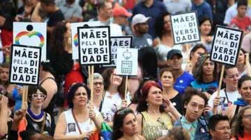 Mulheres segundando placas que dizem " Mães pela diversidade" caminham em passeata